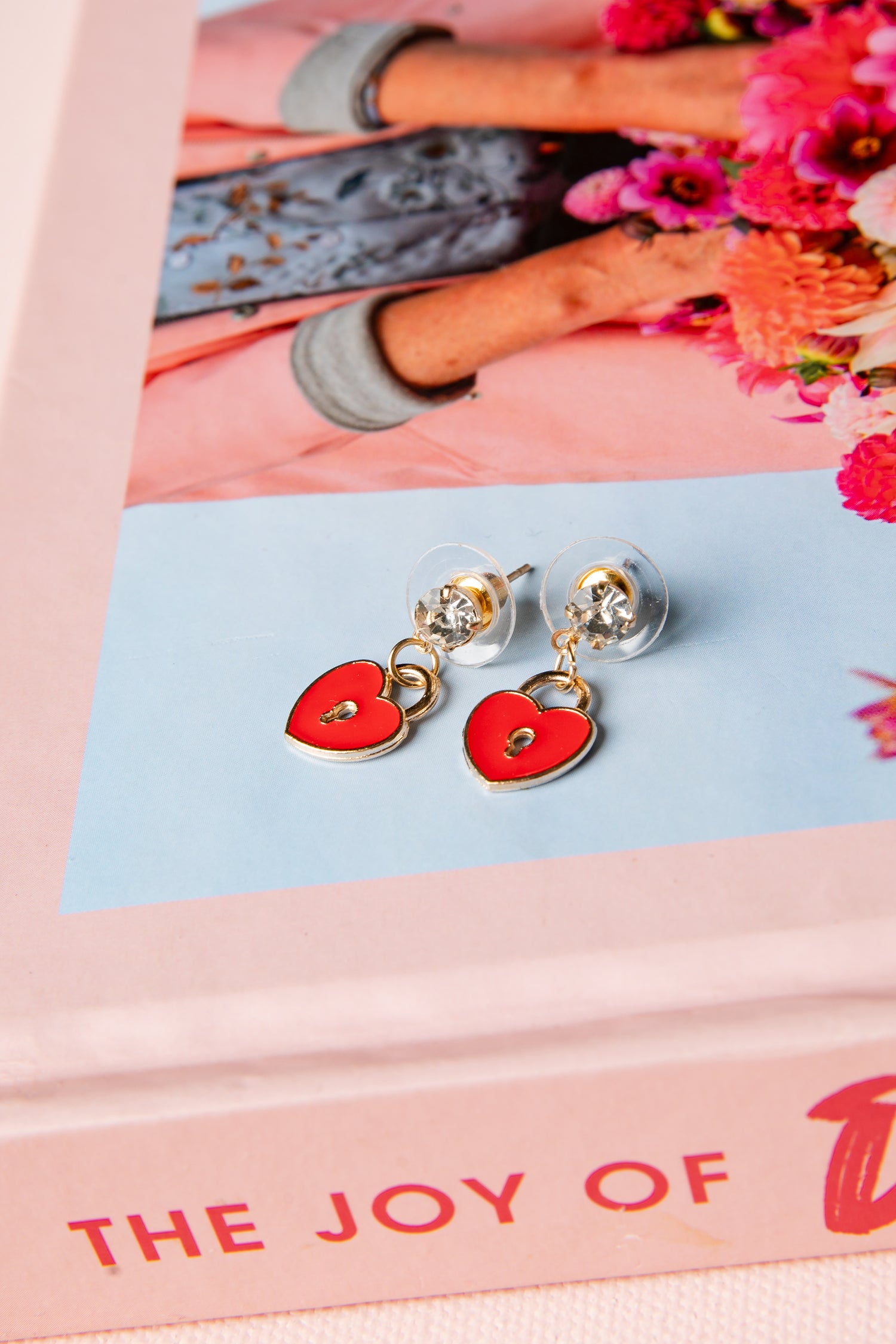Heart-shaped earrings on a pink and blue card with floral background