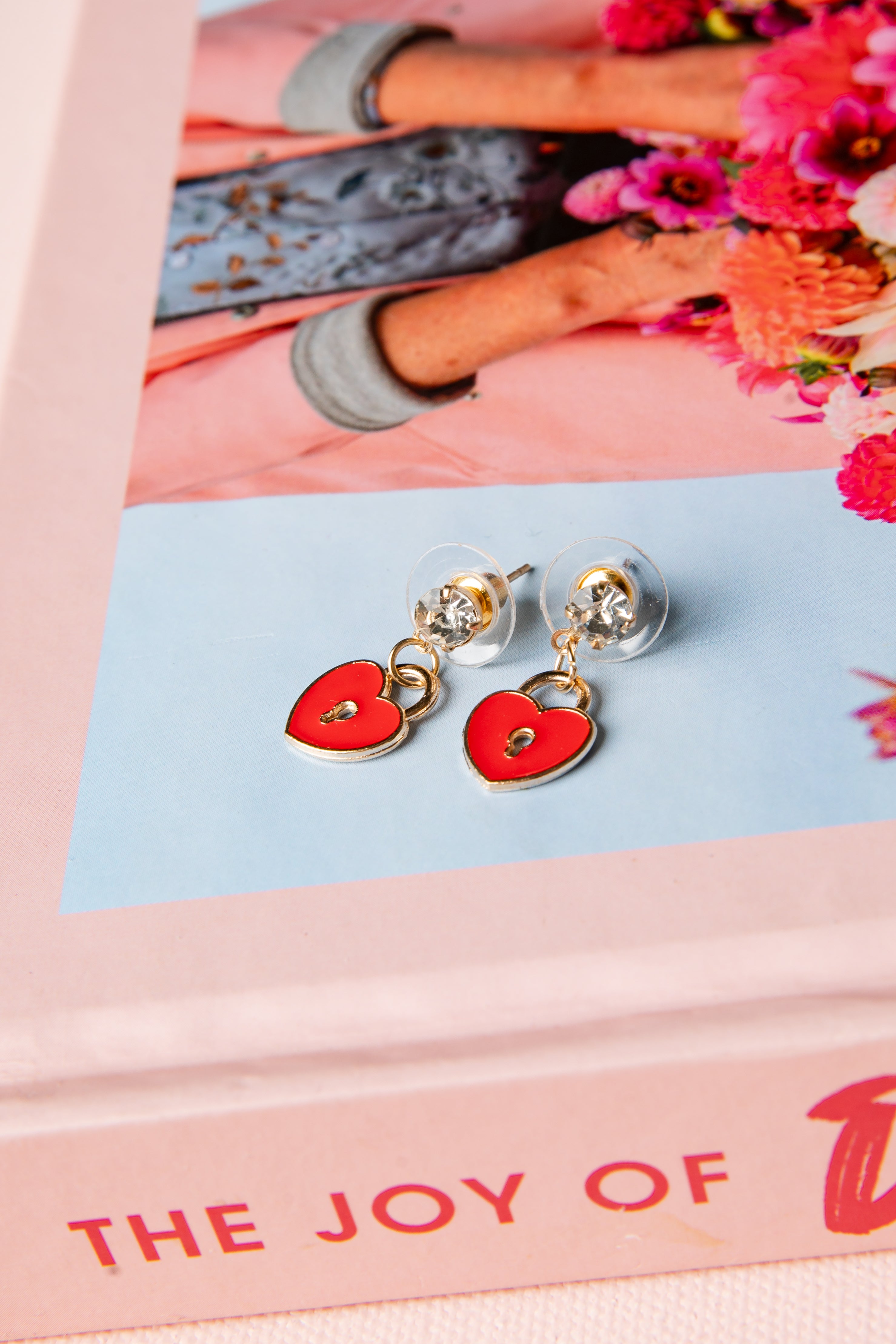 Heart-shaped earrings on a pink and blue card with floral background