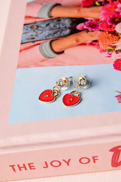 Heart-shaped earrings on a pink and blue card with floral background