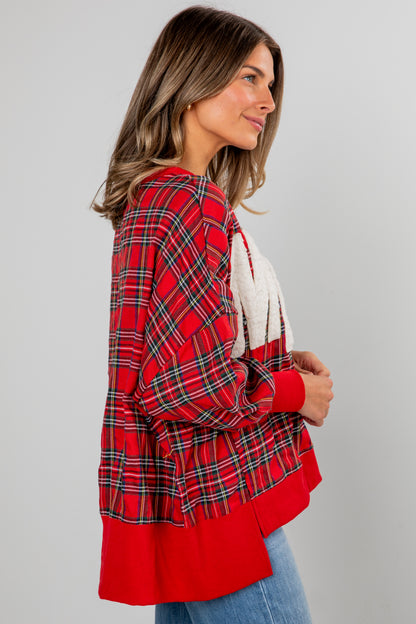 Woman wearing a red plaid jacket over a white top on a gray background