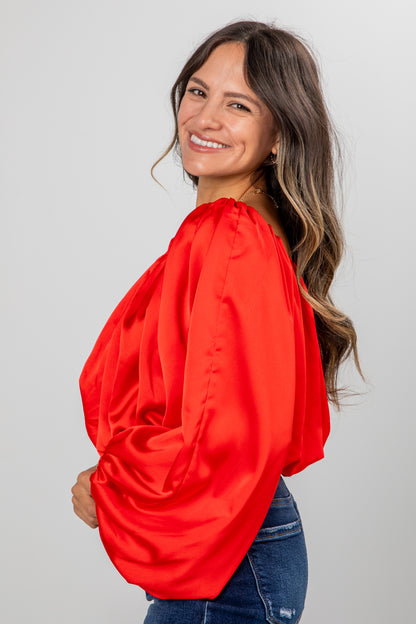 Woman wearing a bright red blouse against a plain background
