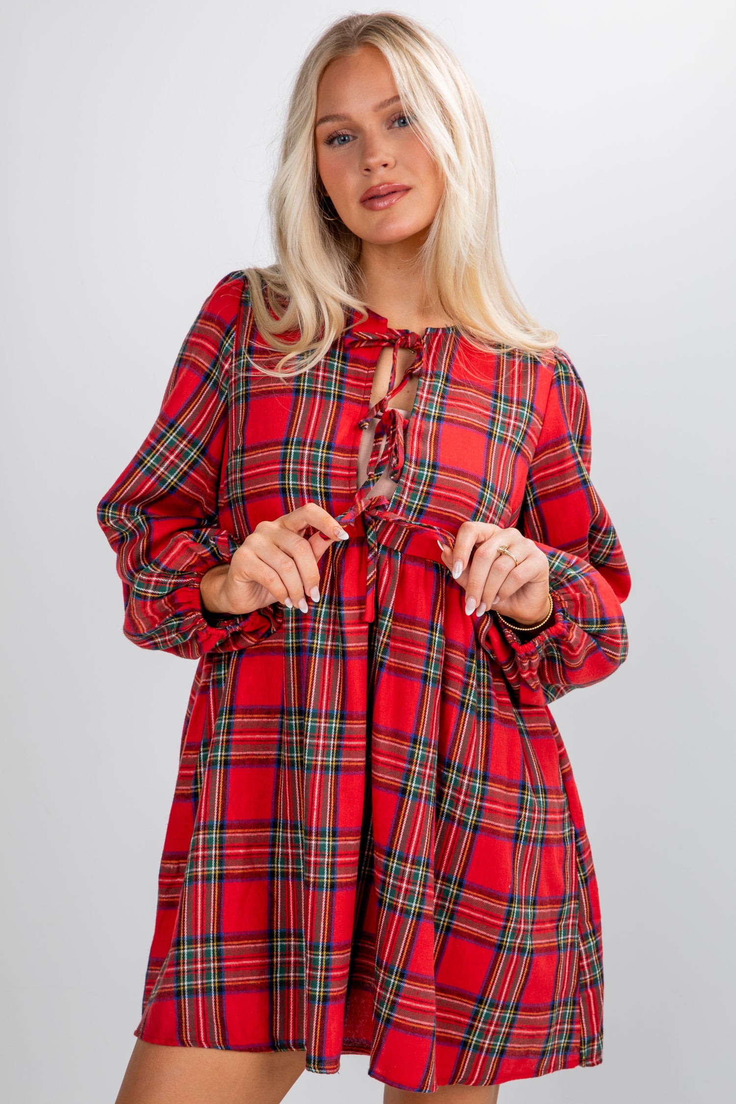 Woman wearing a red plaid dress against a plain background