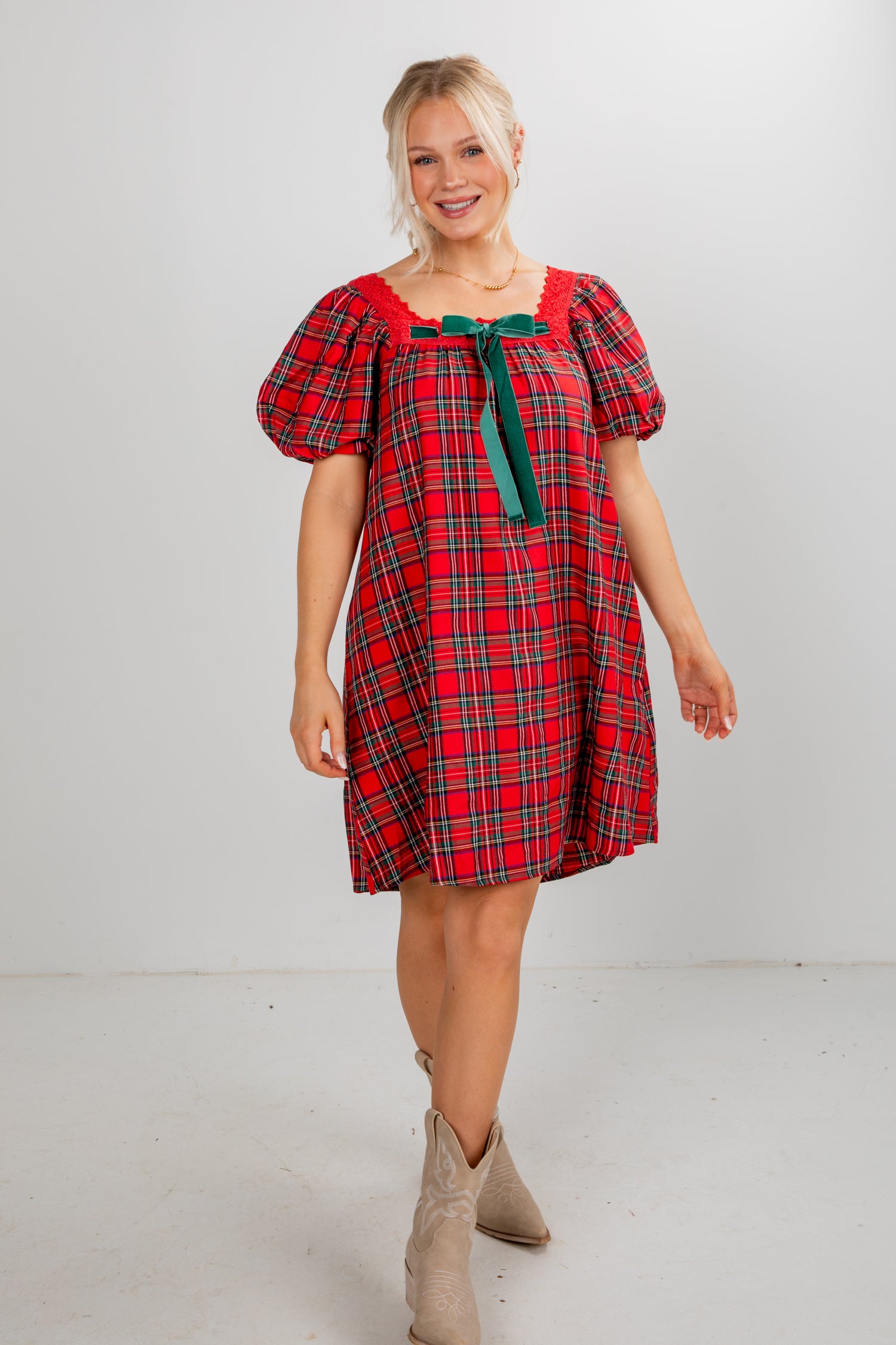 Woman wearing a red plaid dress with puff sleeves on a white background