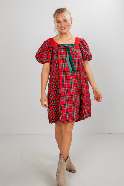 Woman wearing a red plaid dress with puff sleeves on a white background