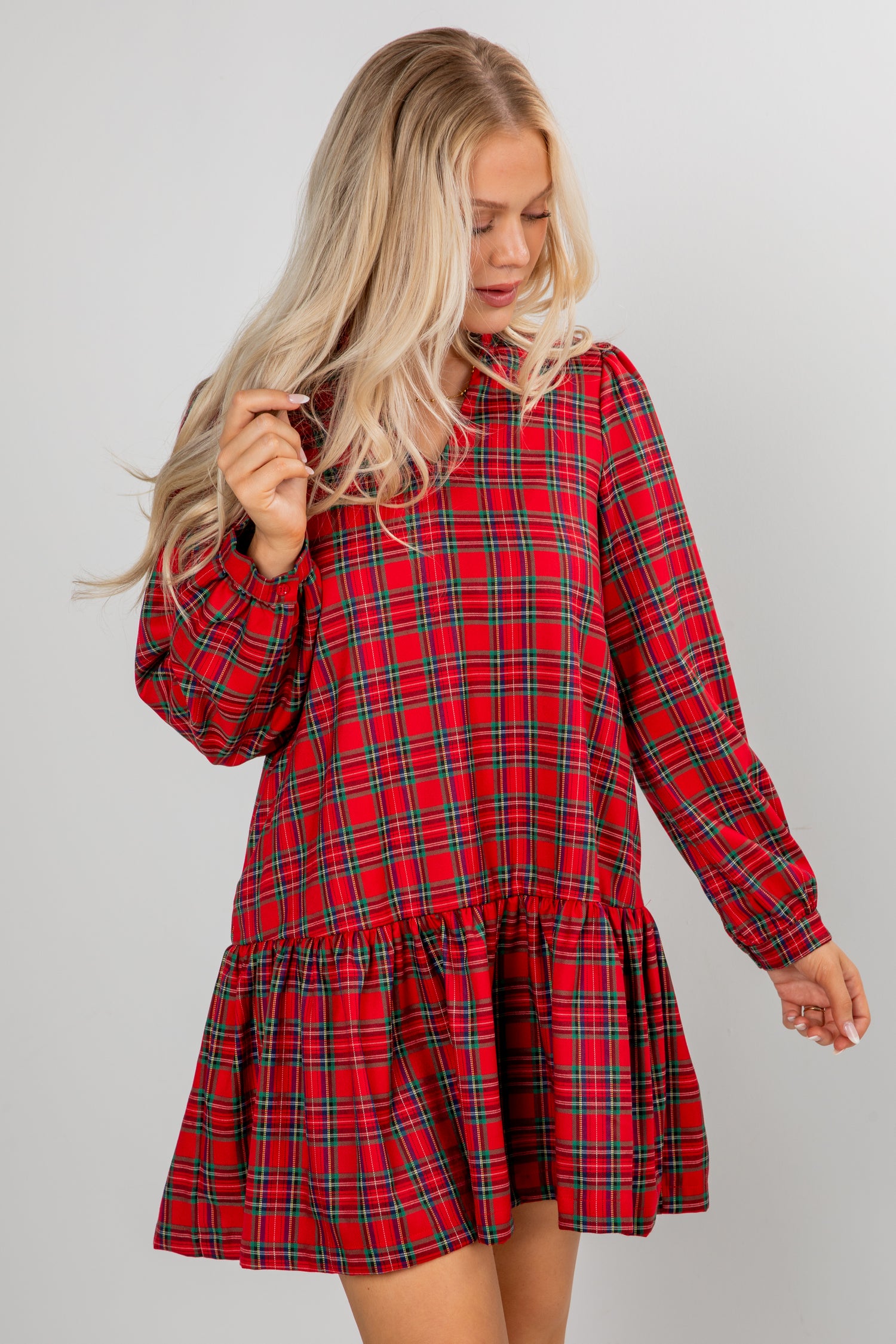 Woman wearing a red plaid dress against a gray background