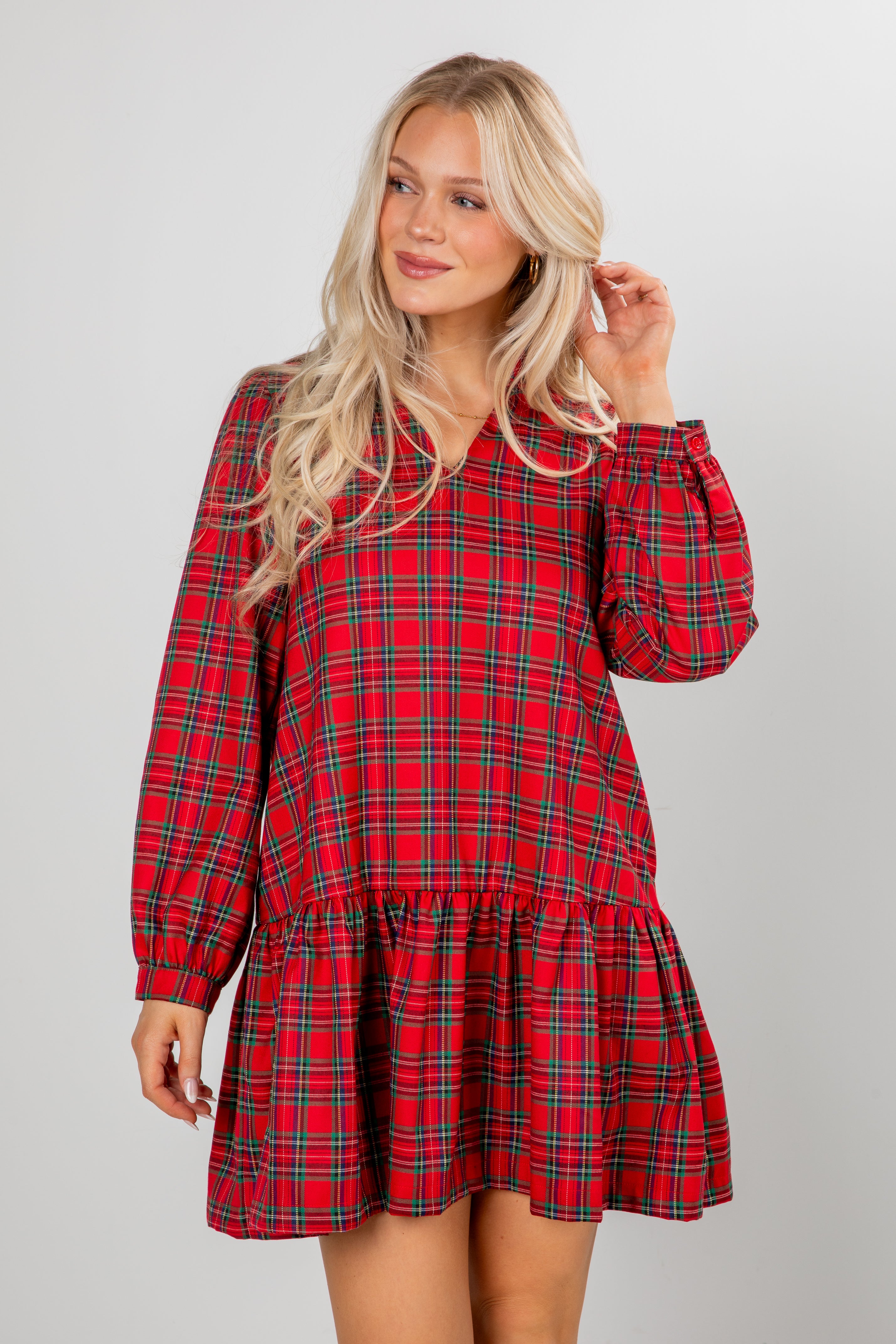 Woman wearing a red plaid dress against a plain background
