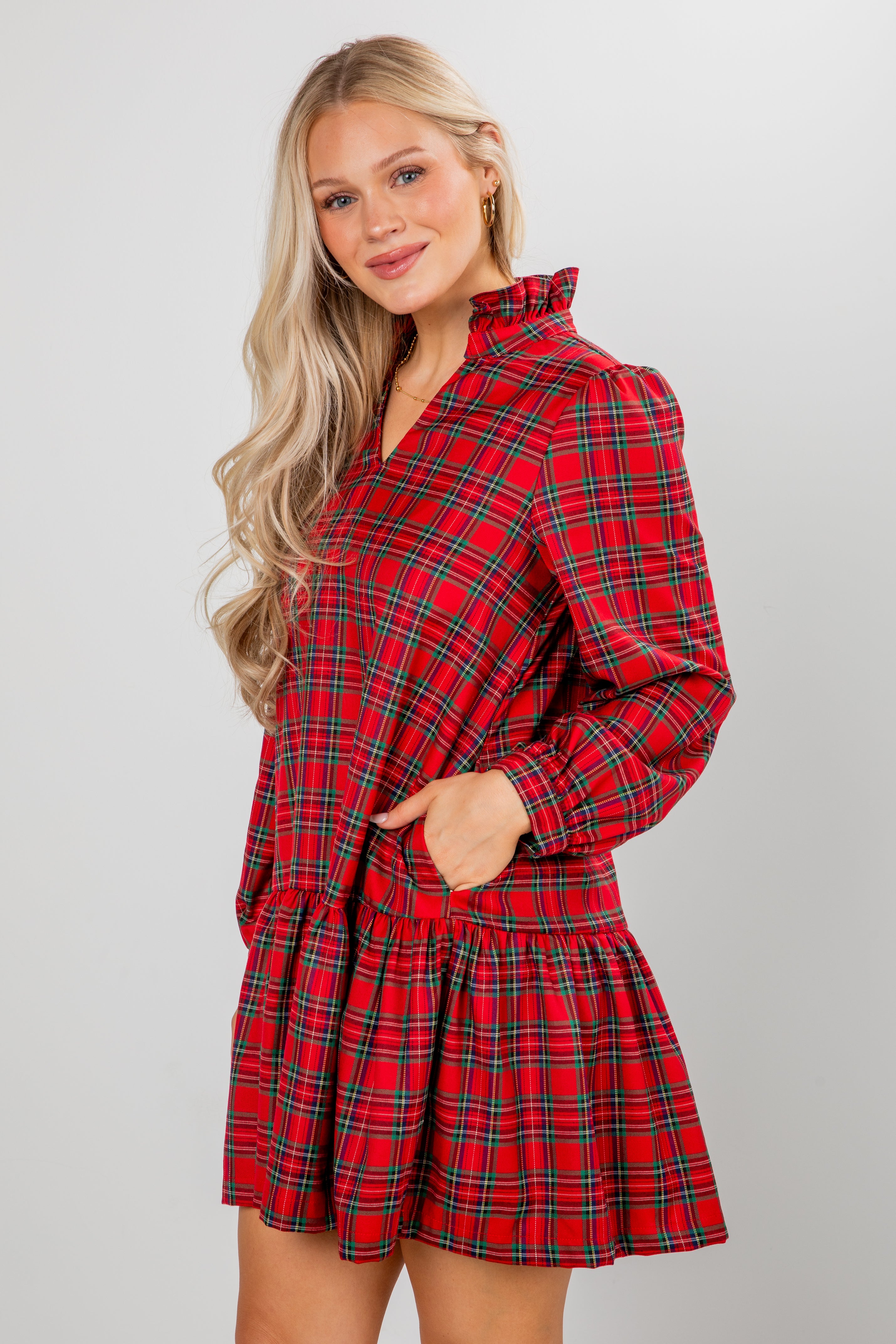 Woman wearing a red plaid dress against a plain background