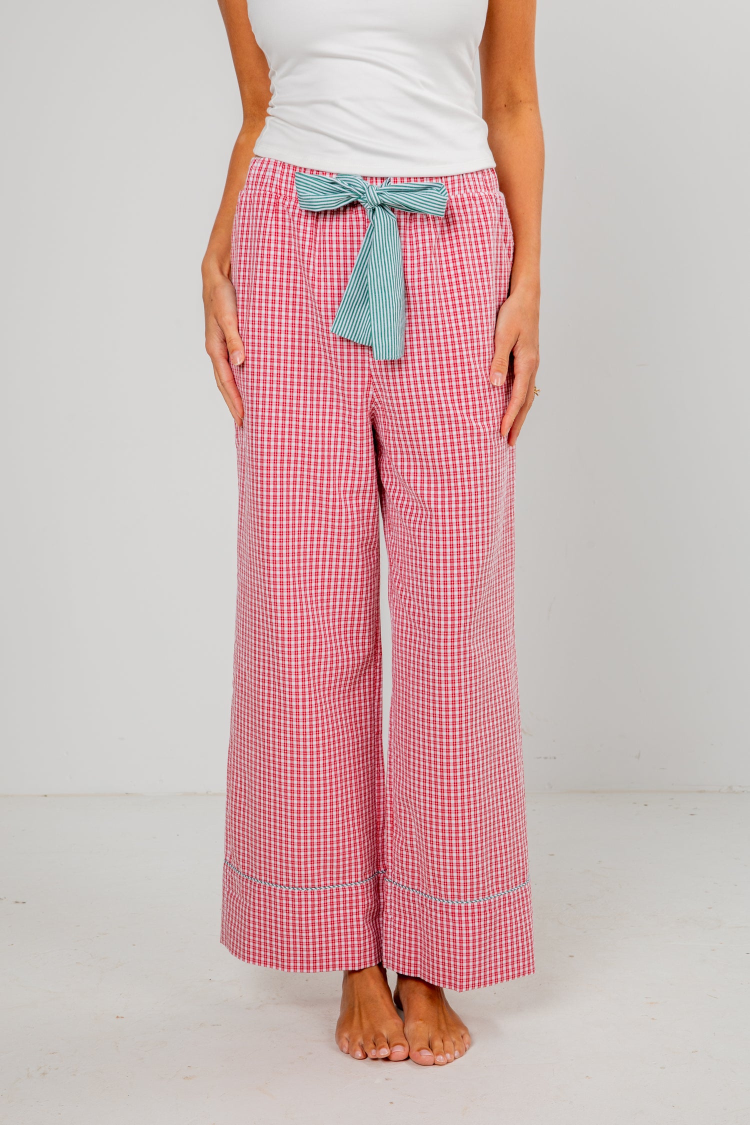 Person wearing red checkered pants with a blue bow tie on a white background