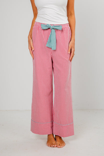 Person wearing red checkered pants with a blue bow tie on a white background