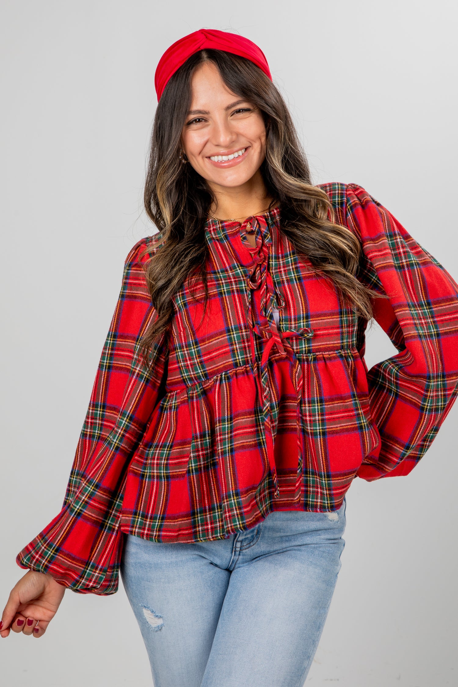 Woman wearing a red plaid top and jeans on a gray background