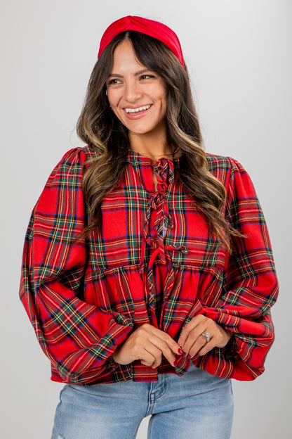 Woman wearing a red plaid blouse and red beret against a gray background