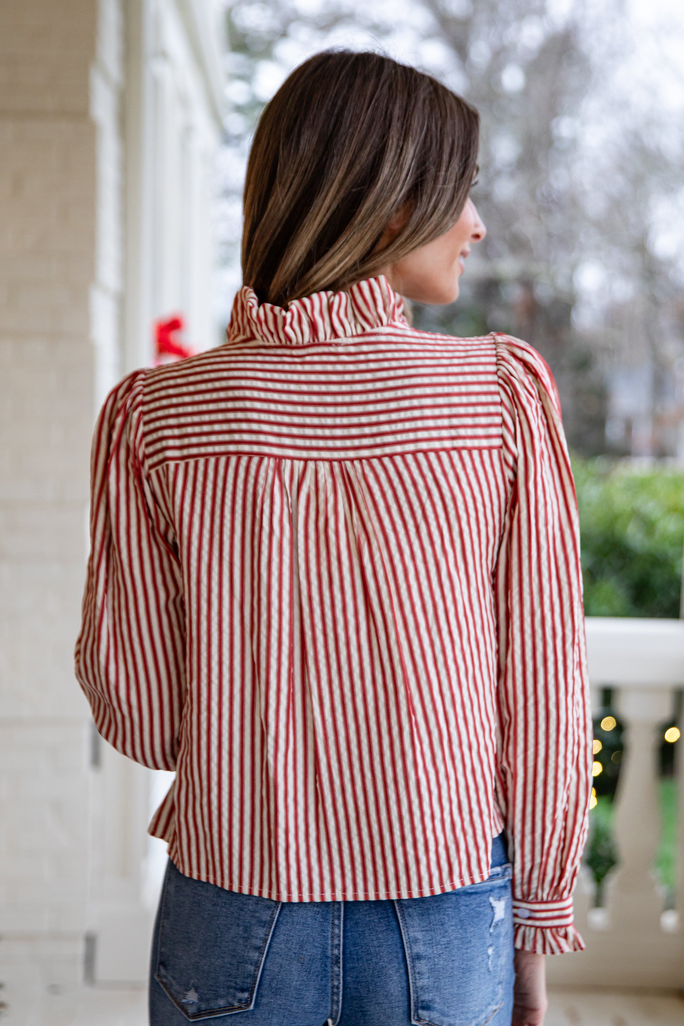 Woman wearing a red and white striped blouse on a porch