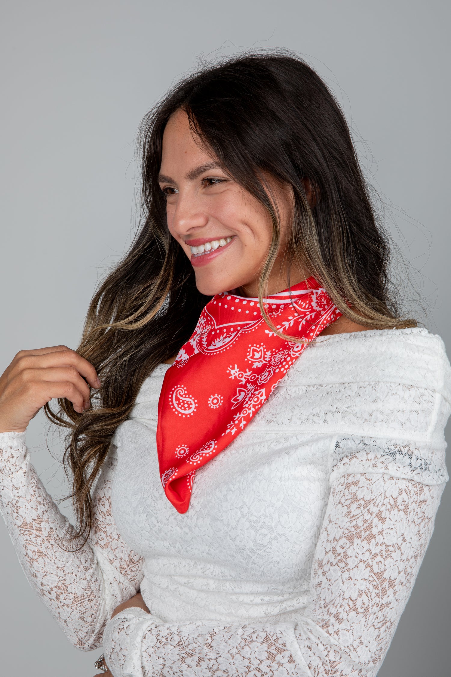 Woman wearing a red bandana and white lace top against a gray background