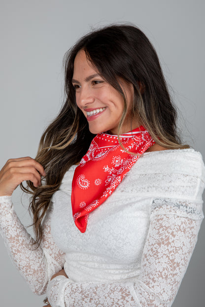 Woman wearing a red bandana and white lace top against a gray background
