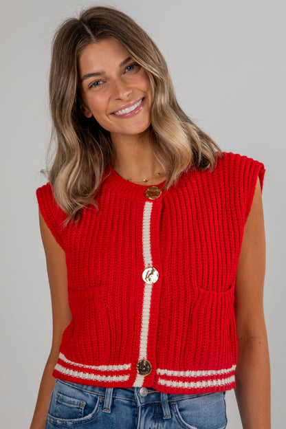 Woman wearing a red knitted vest with white trim on a gray background