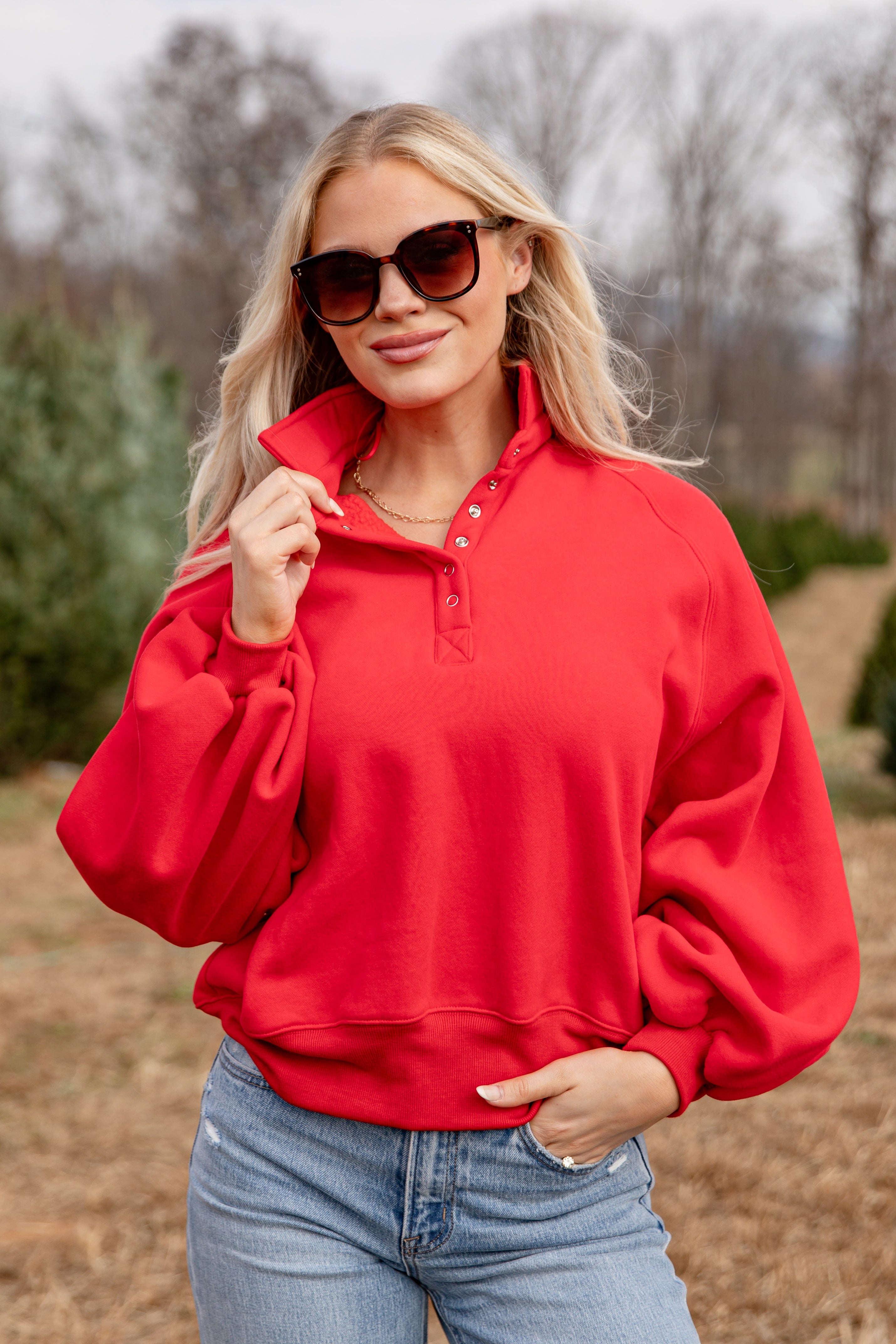 Woman wearing a red pullover and sunglasses outdoors