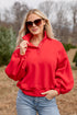 Woman wearing a red pullover and sunglasses outdoors