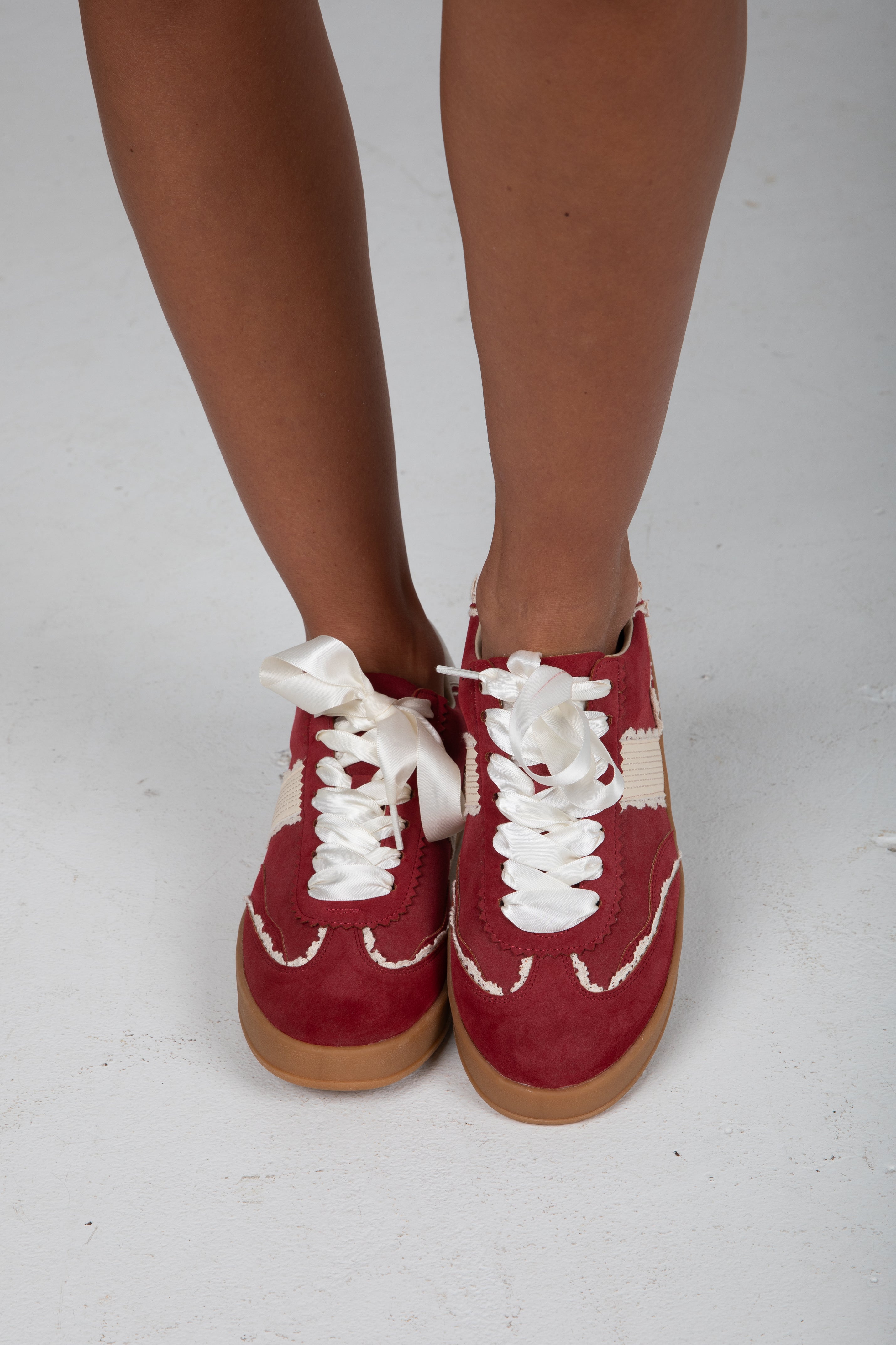Red sneakers with white laces on a plain background