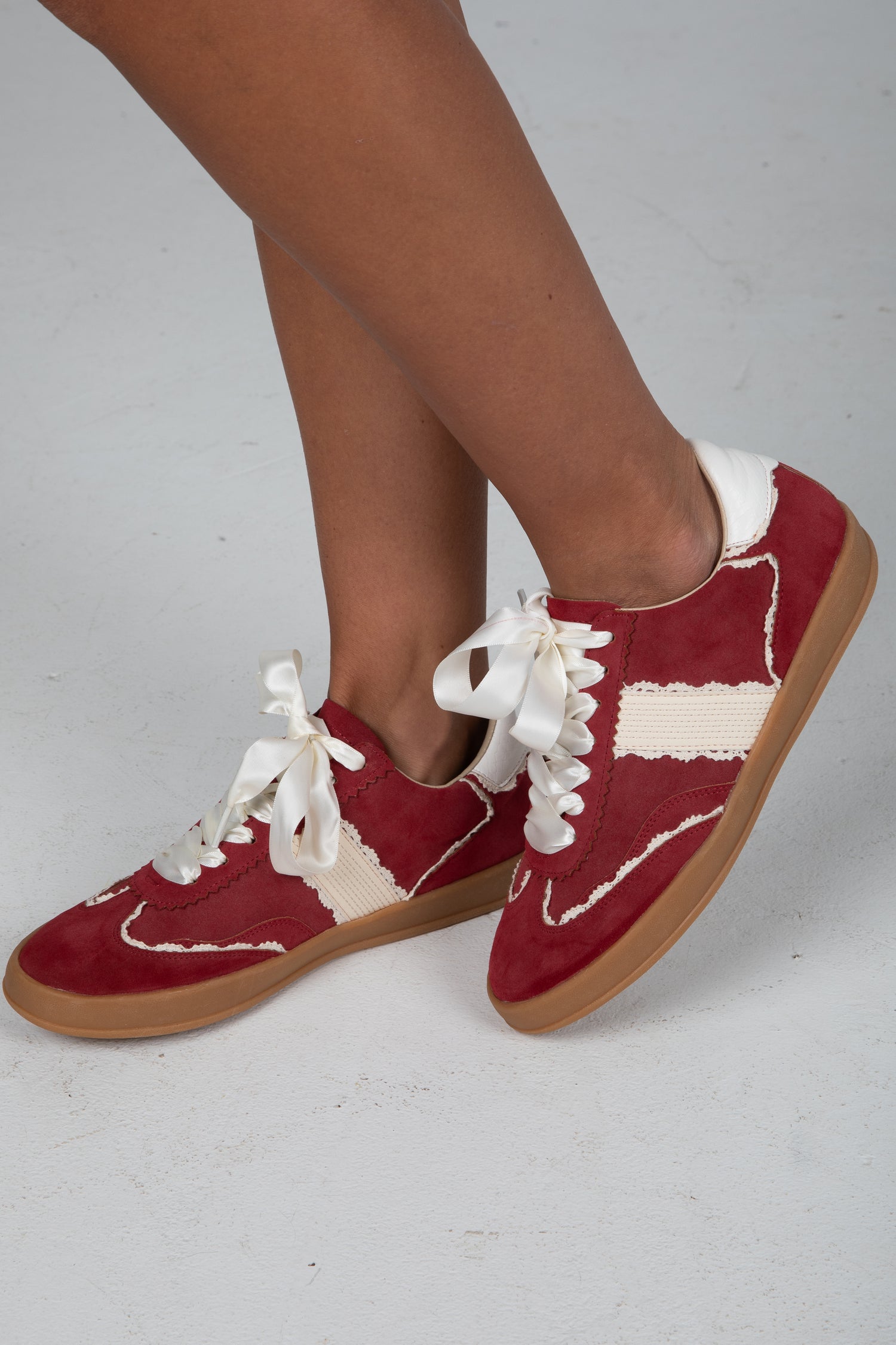 Red sneakers with white laces and accents on a light gray background
