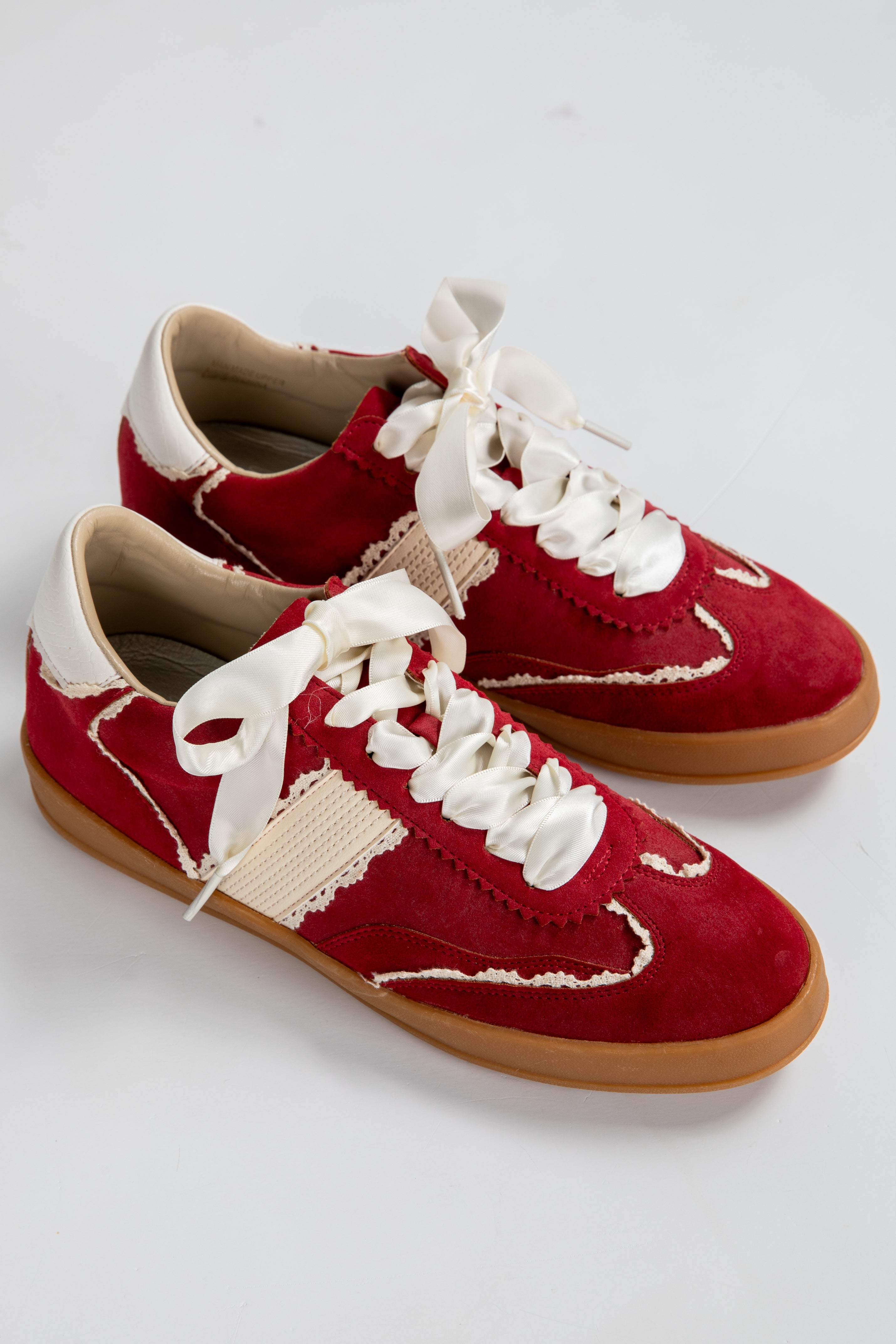 Red sneakers with white laces on a light gray background