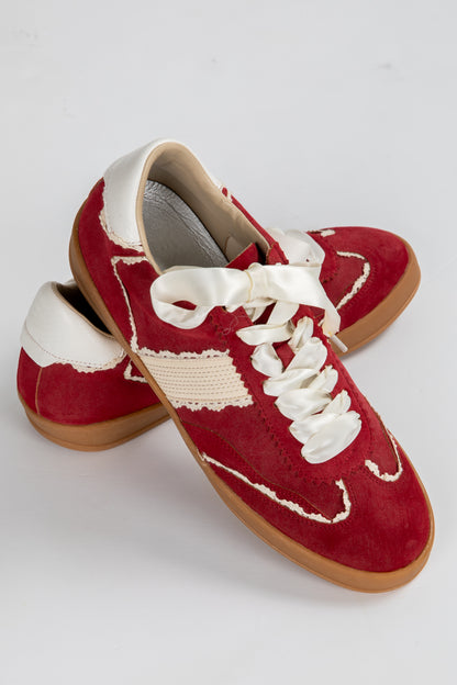 Red sneakers with white laces on a light gray background