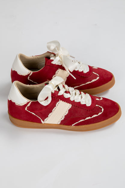 Red and white sneakers with brown soles on a light gray background