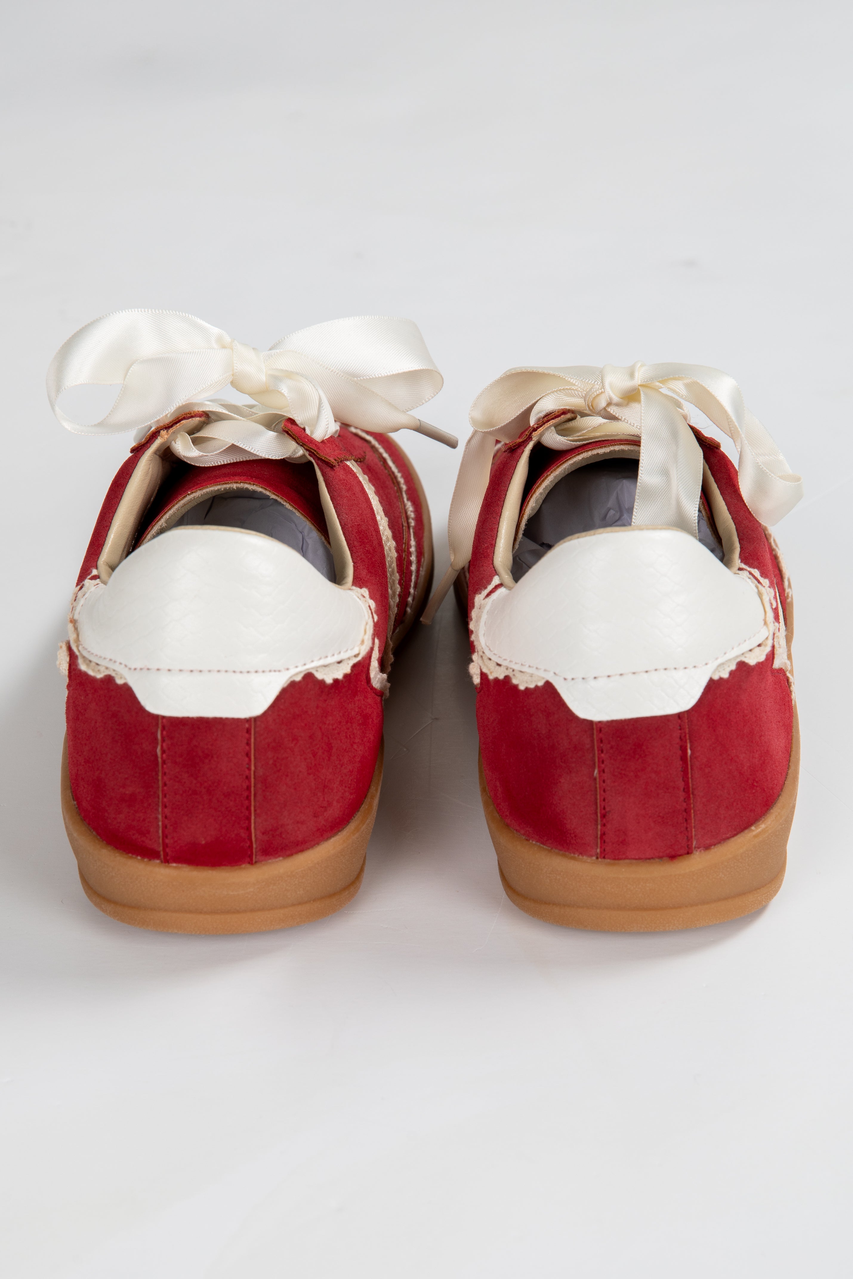 Red shoes with white laces and soles on a light gray background