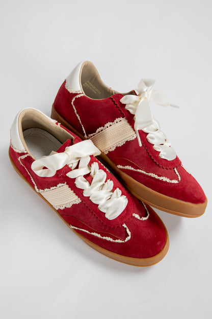 Red sneakers with white laces on a light gray background