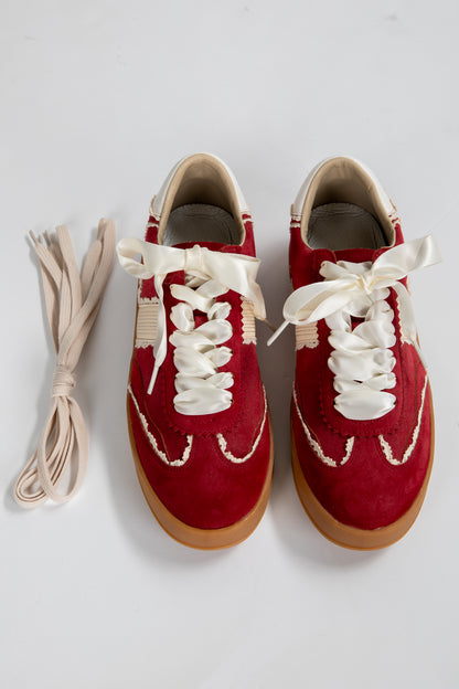 Red sneakers with white laces on a light gray background