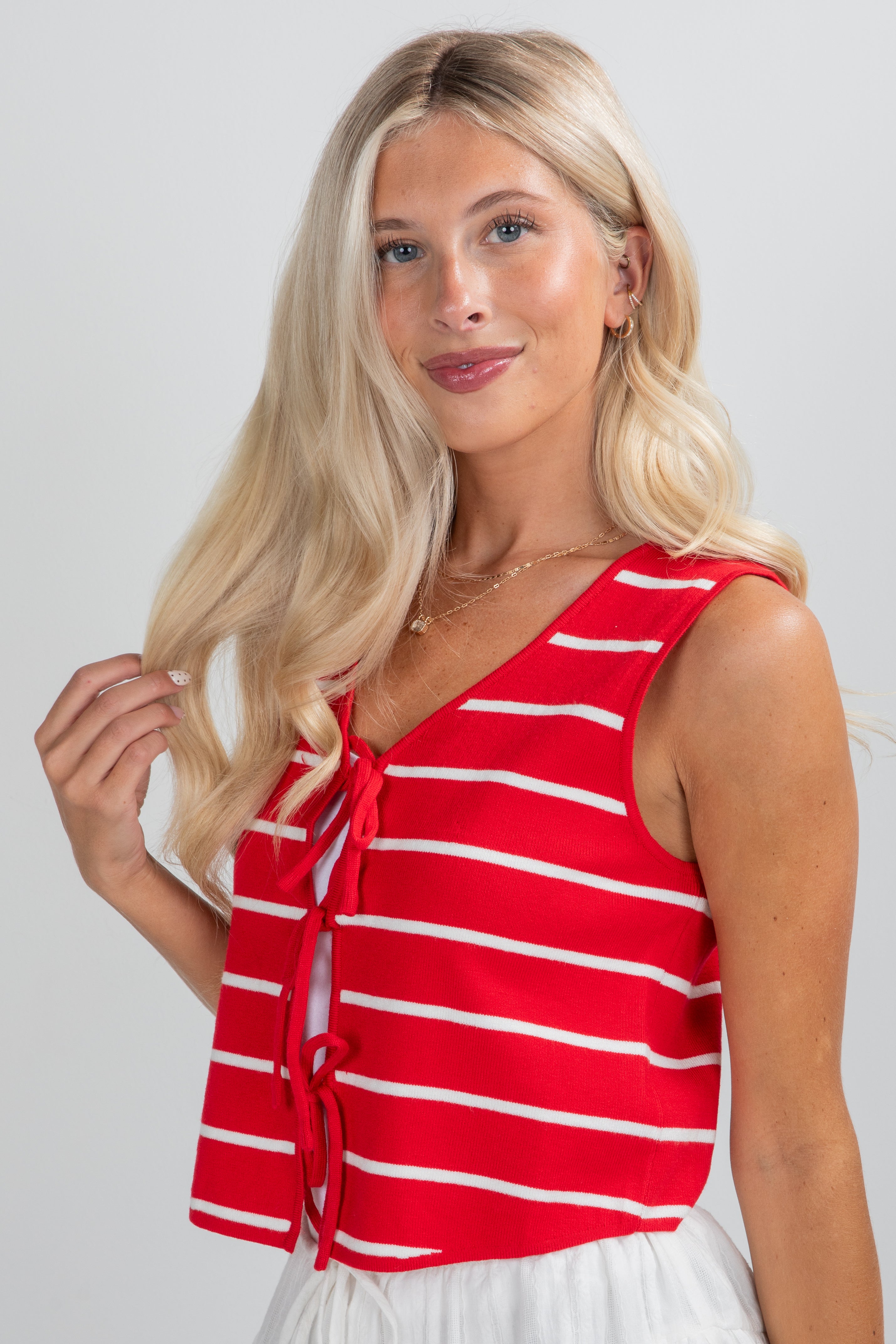Woman wearing a red and white striped sleeveless top against a plain background