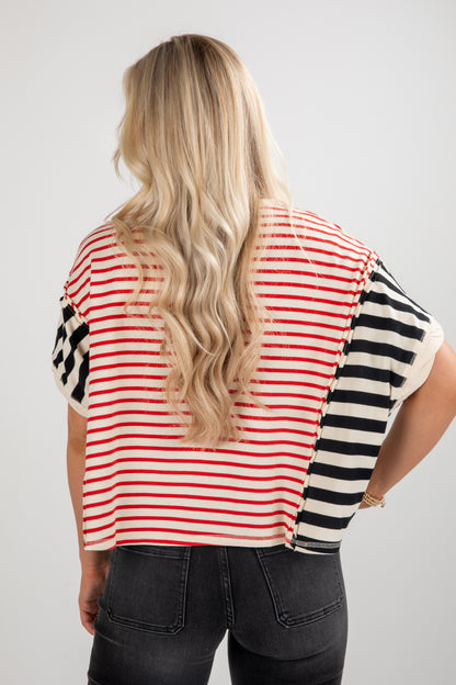 Person wearing a striped shirt with red, white, and black pattern on a plain background