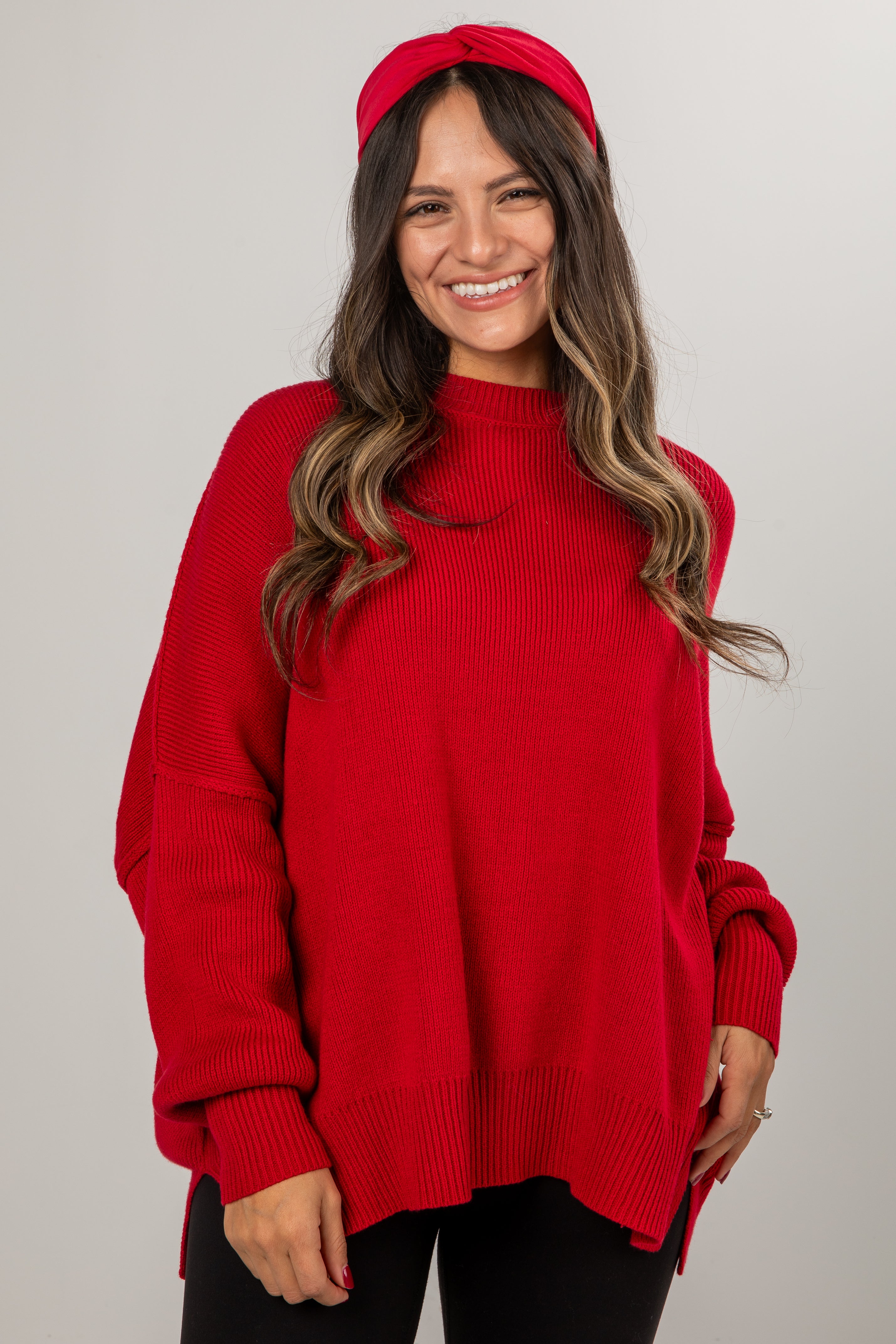 Woman wearing a red sweater and headband against a plain background