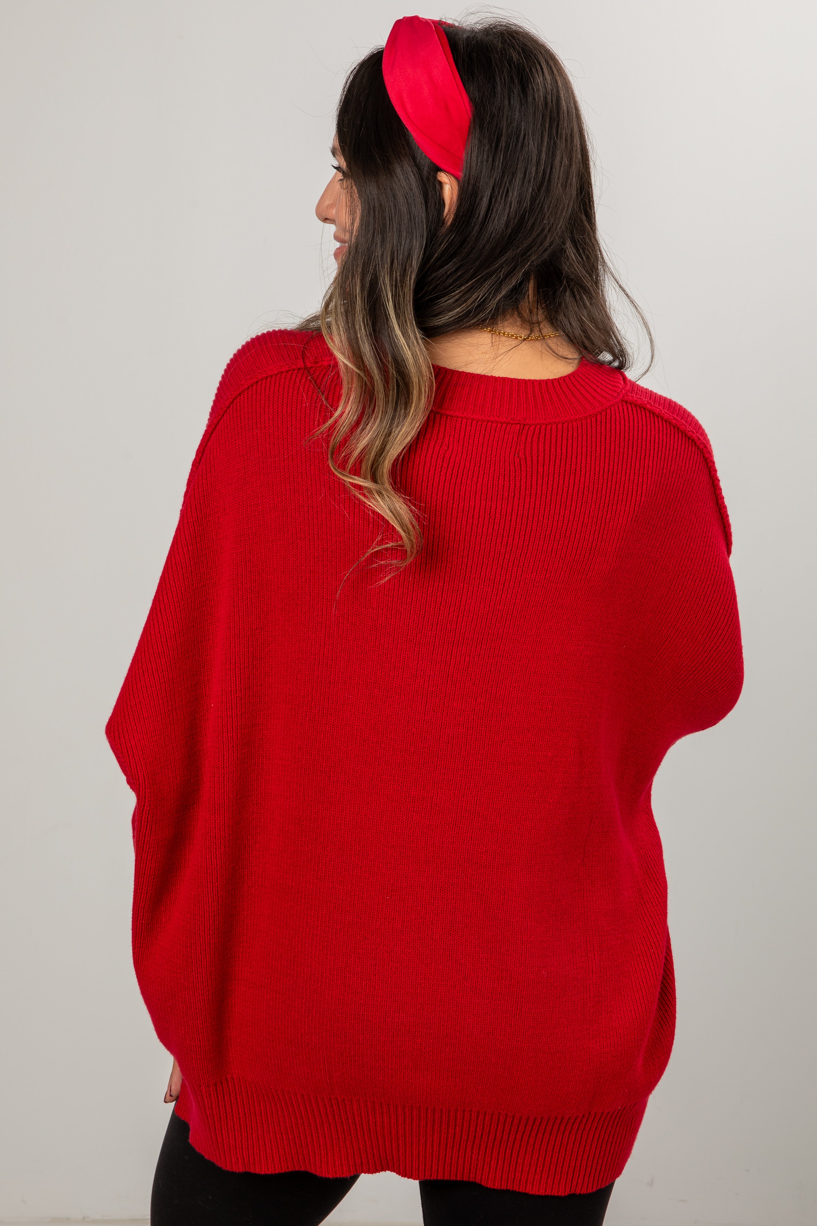 Person wearing a red sweater and red headband against a plain background