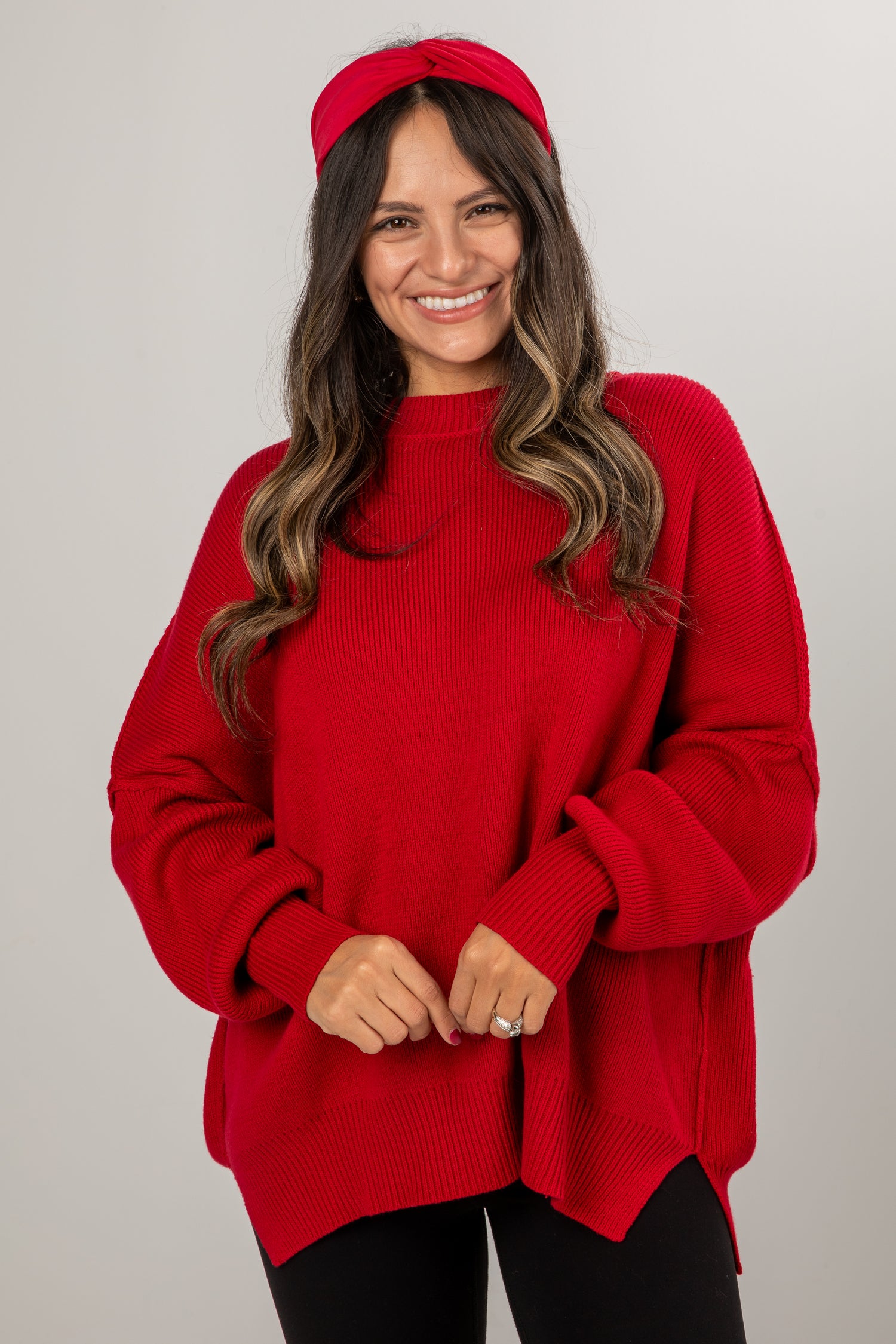Woman wearing a red sweater and headband against a plain background