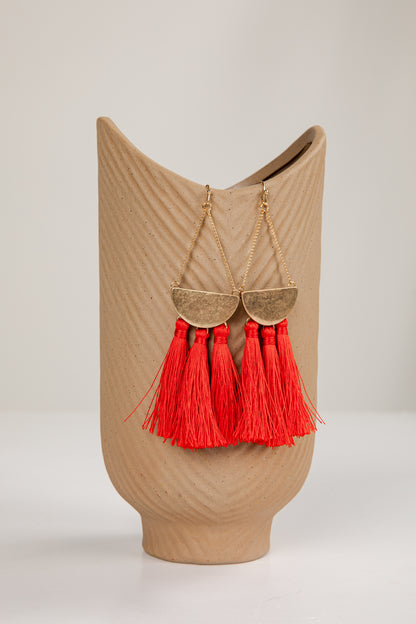 Beige decorative vase with red tassels on a light gray background