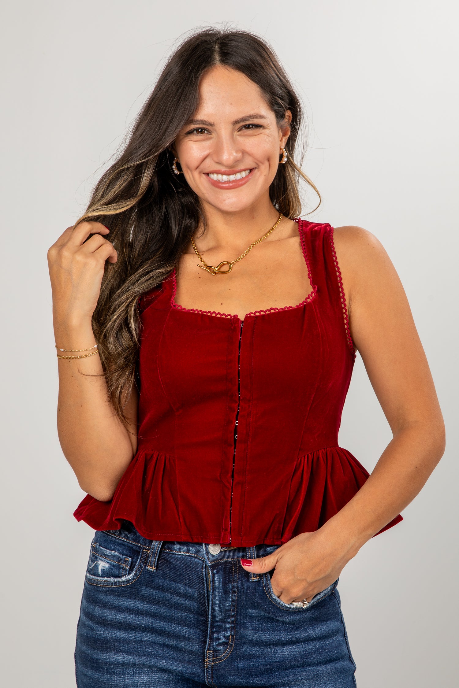 Woman wearing a red top and blue jeans against a plain background