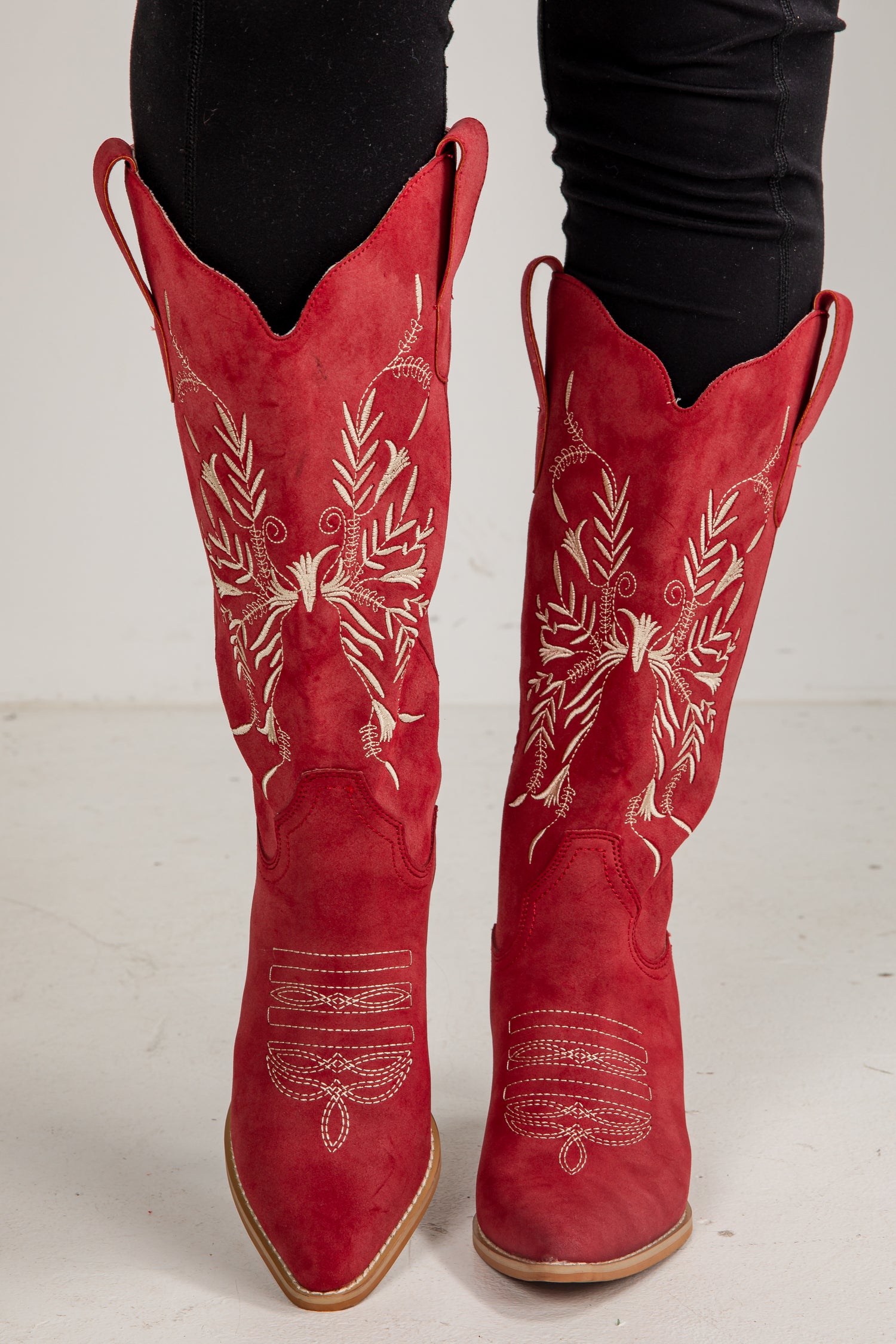 Red cowboy boots with white embroidery on a white background
