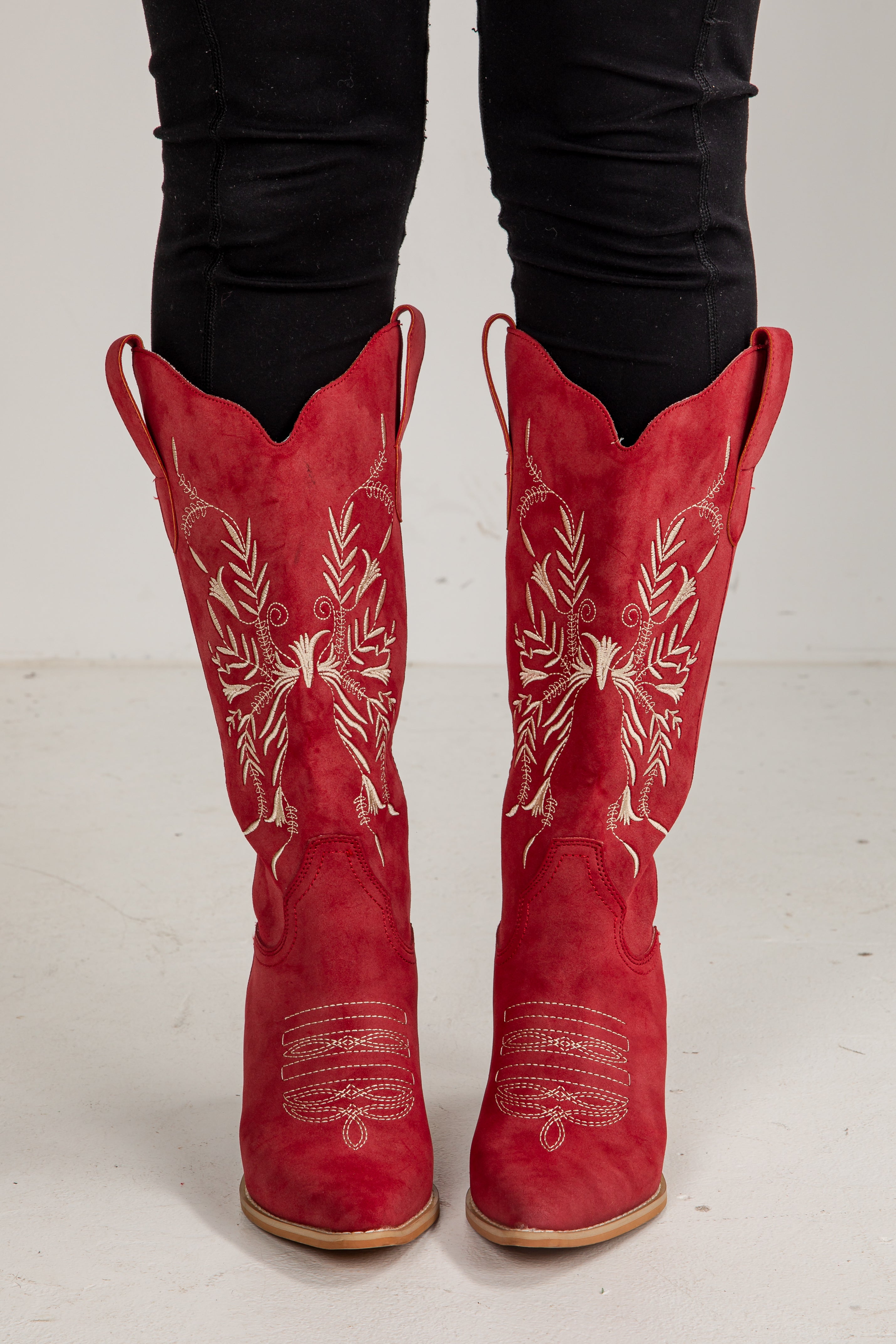 Red cowboy boots with white embroidery on a white background