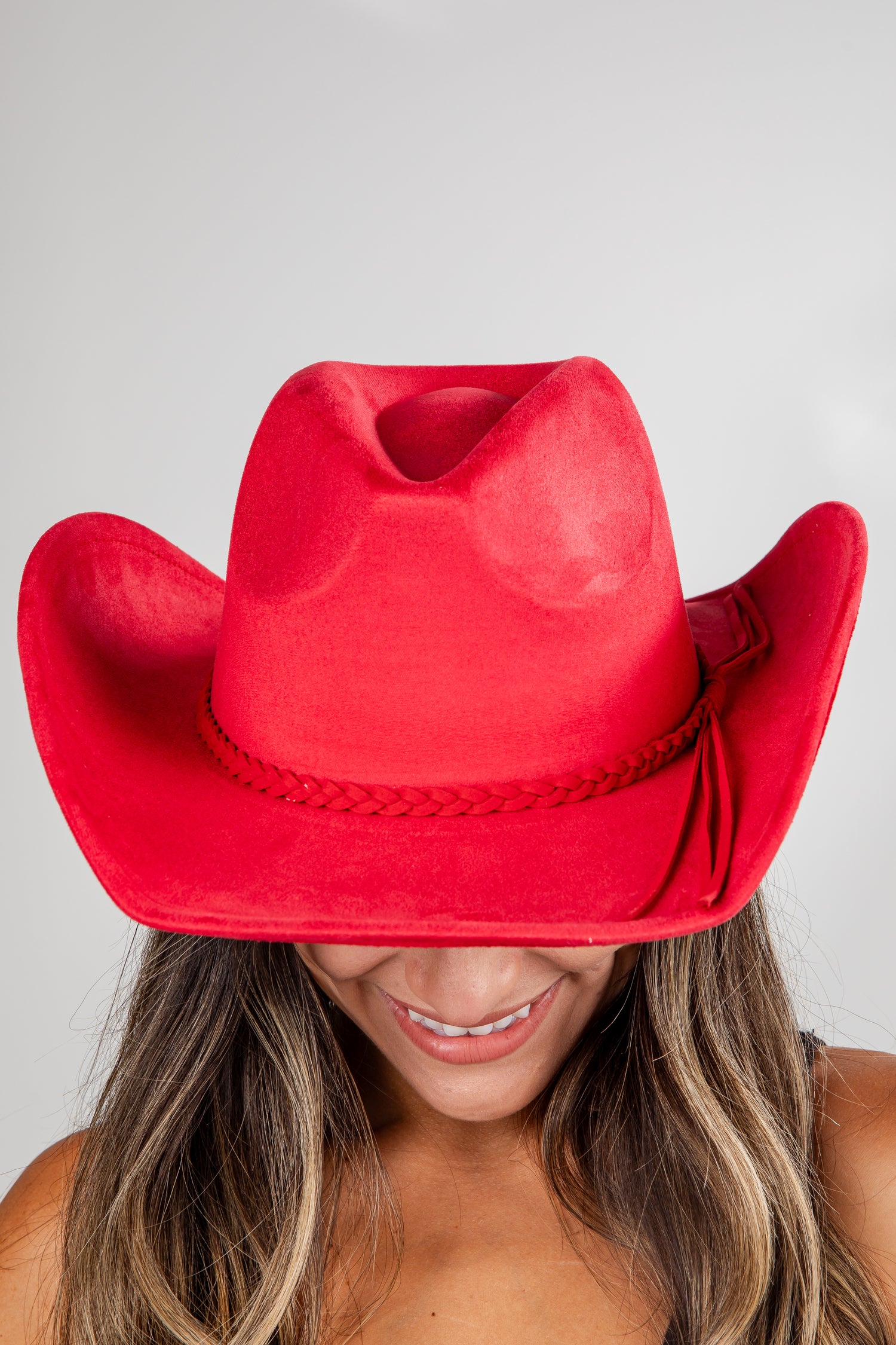 Red cowboy hat worn by a person on a plain background