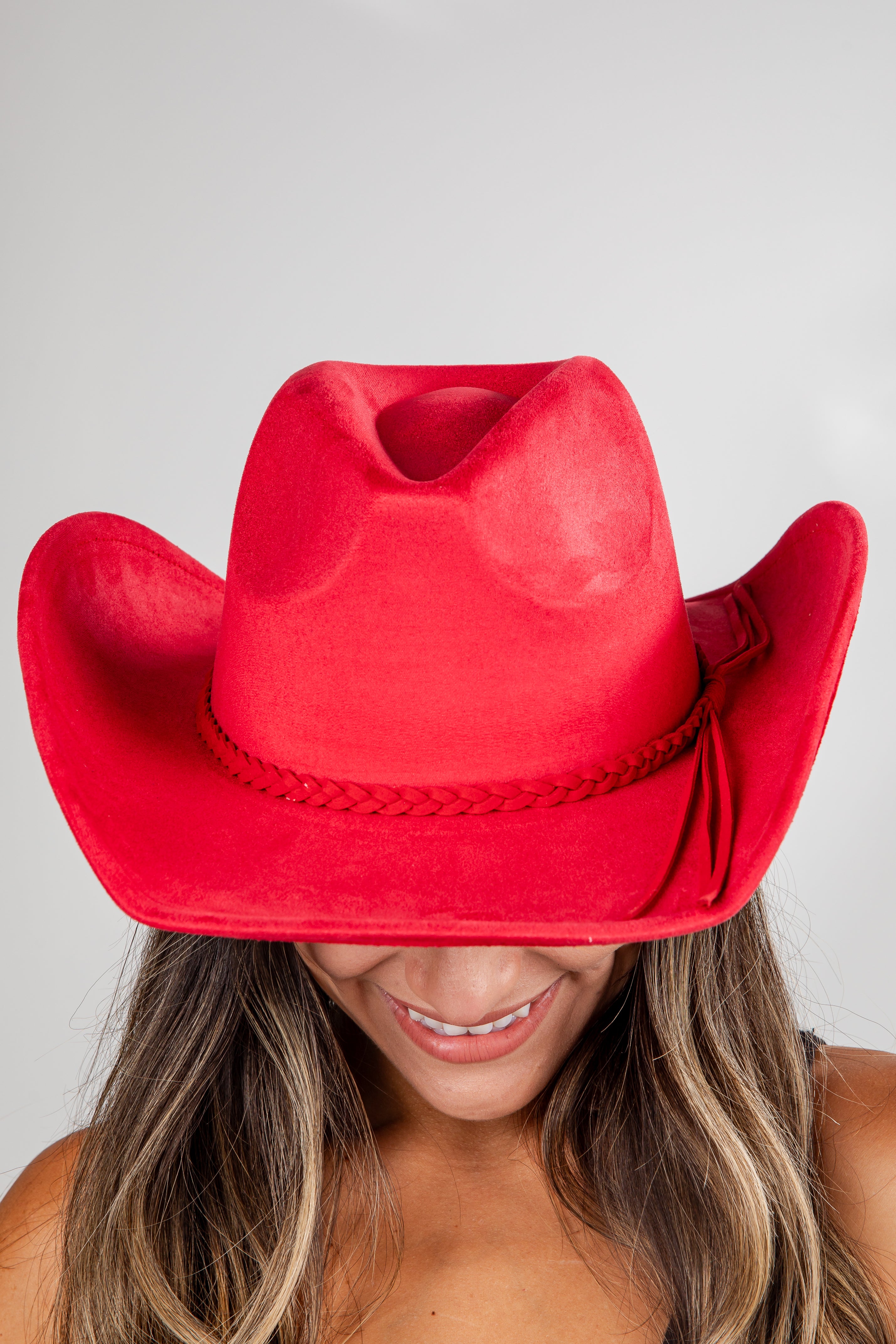 Red cowboy hat worn by a person on a plain background