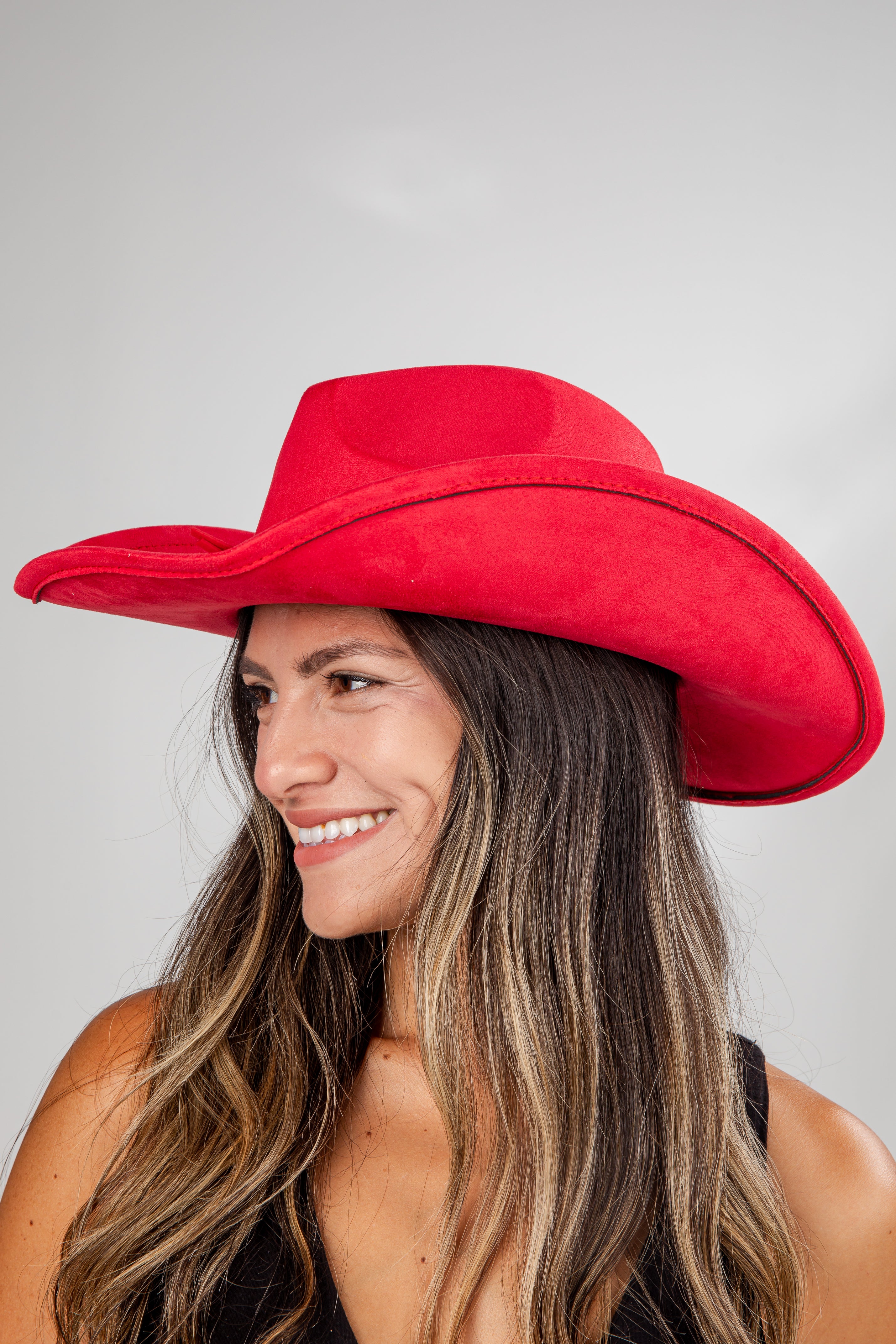 Woman wearing a red cowboy hat against a gray background