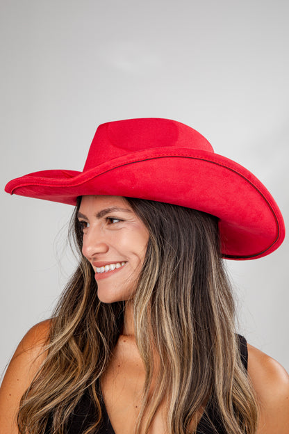 Woman wearing a red cowboy hat against a gray background