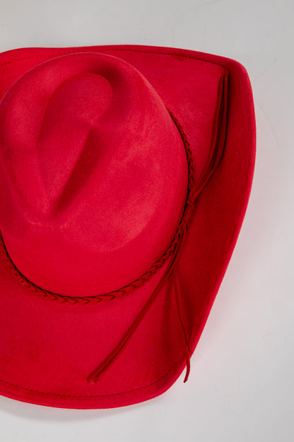Red cowboy hat with a feather on a light gray background