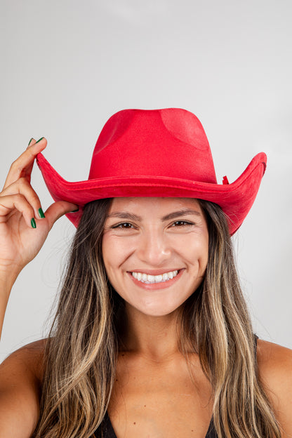 Woman wearing a red cowboy hat against a plain background