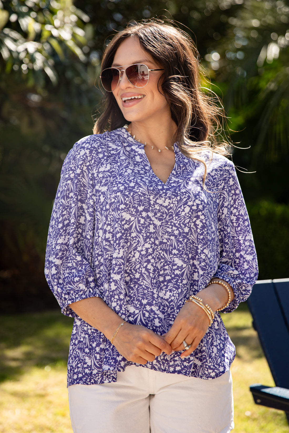 Woman wearing a blue floral blouse and sunglasses outdoors