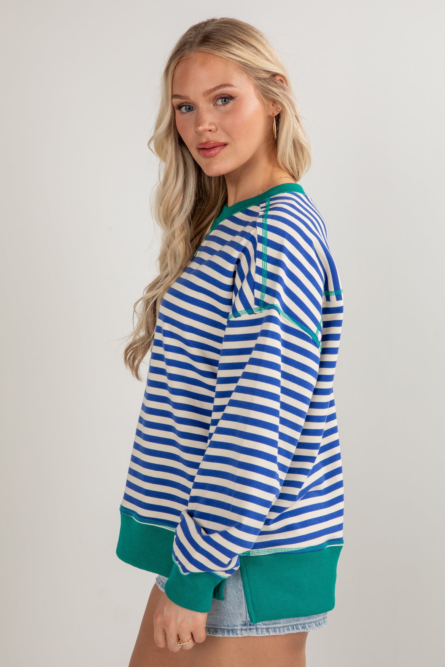 Woman wearing a blue and white striped shirt with green trim on a plain background