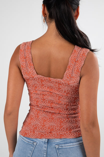 Woman wearing a patterned orange top and blue jeans on a white background