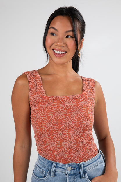 Woman wearing a patterned orange top and blue jeans on a white background