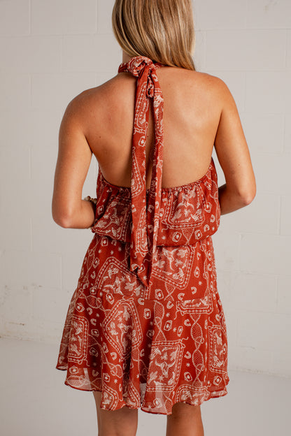 rust mini dress features an ivory paisley print, a flattering halter neckline, and a flowy silhouette