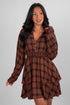 Woman wearing a brown plaid dress against a gray background